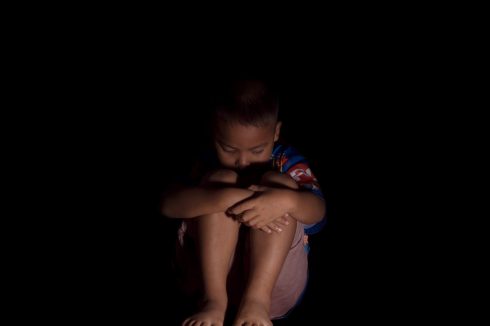 Sad child sitting barefoot