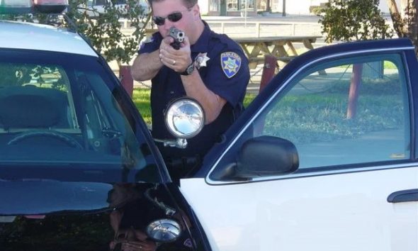 Police officer with gun drawn